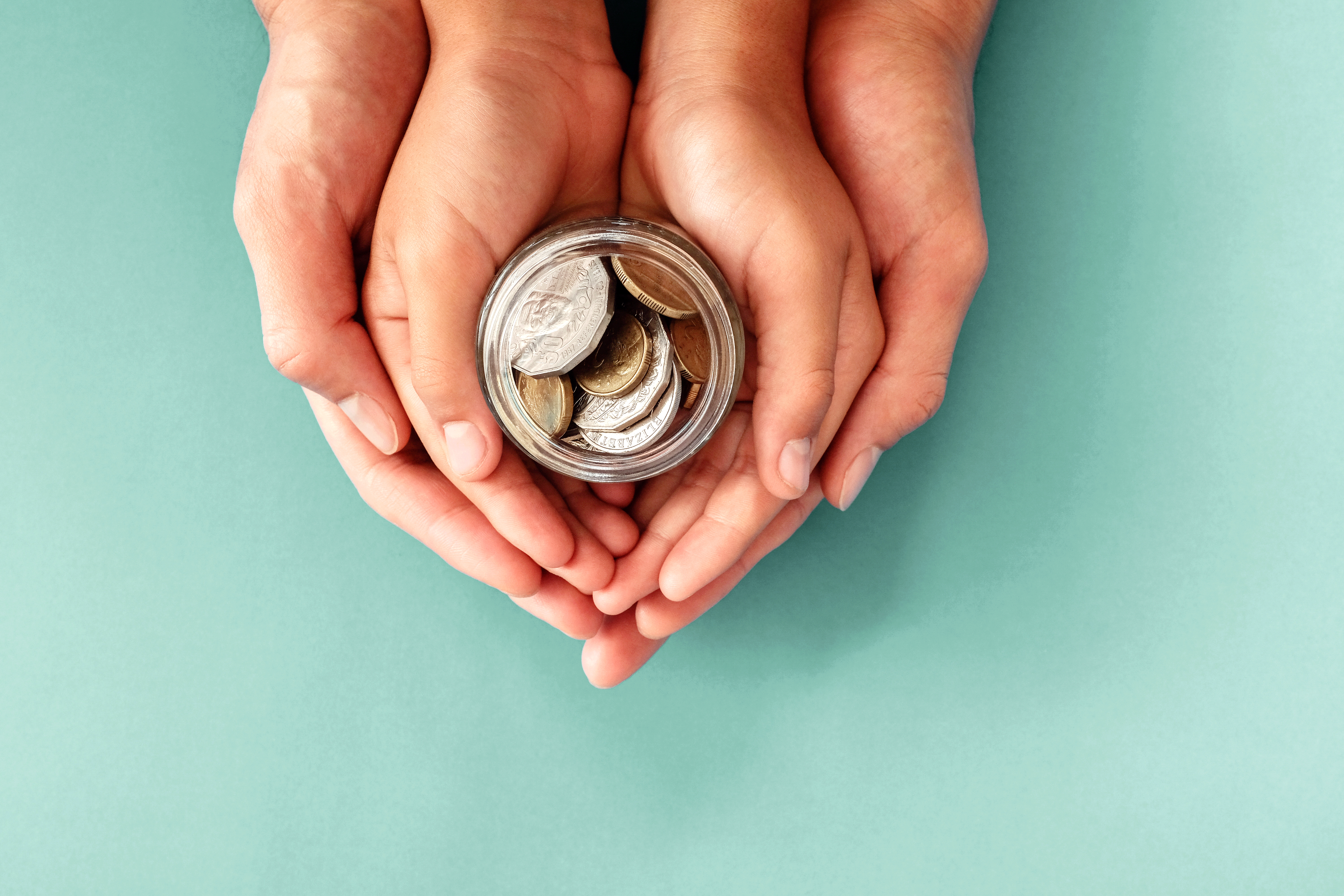 child and parent hands holding money jar, donation, saving, family finance plan concept